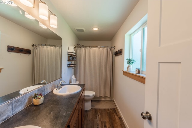 bathroom with visible vents, a shower with curtain, toilet, vanity, and wood finished floors