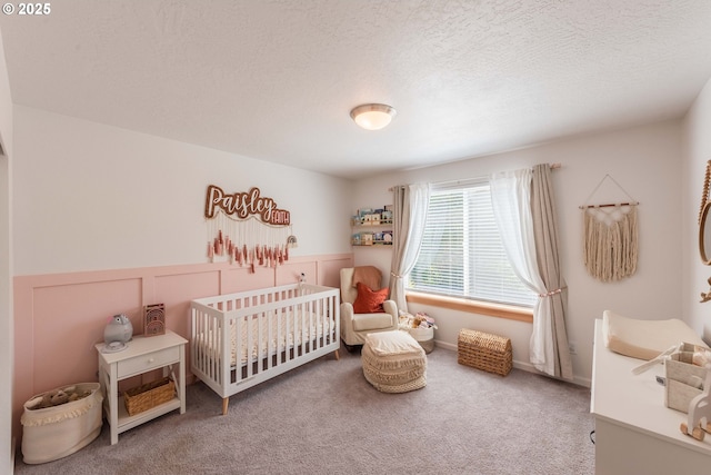 carpeted bedroom with a nursery area and a textured ceiling