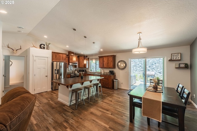 interior space with brown cabinetry, a center island, dark wood-style flooring, dark countertops, and stainless steel appliances