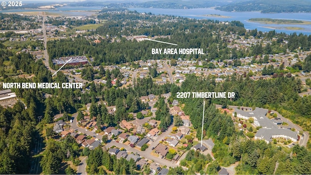 drone / aerial view featuring a water view, a wooded view, and a residential view