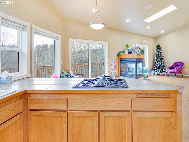 kitchen with open floor plan, stainless steel gas stovetop, tile countertops, and wood finished floors