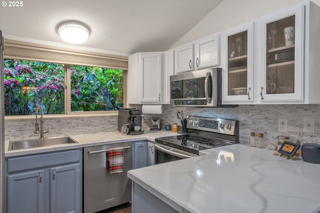 178 SW The Pines Dr, Depoe Bay, OR 97341 - kitchen with appliances with stainless steel finishes, a sink, vaulted ceiling, white cabinets, and decorative backsplash