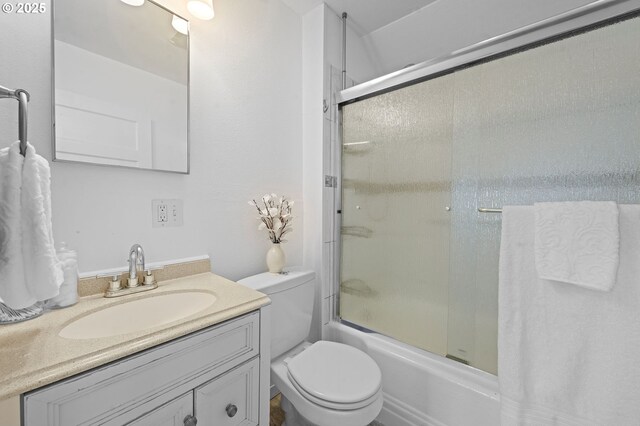 full bath featuring vanity, enclosed tub / shower combo, and toilet