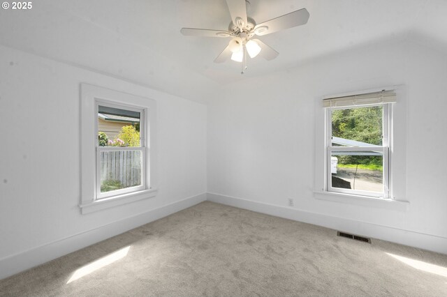 spare room featuring ceiling fan, visible vents, vaulted ceiling, baseboards, and carpet