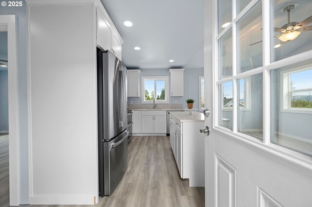 kitchen featuring light wood-type flooring, light countertops, white cabinets, freestanding refrigerator, and recessed lighting