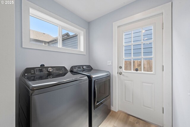 clothes washing area featuring separate washer and dryer, laundry area, and light wood-style floors