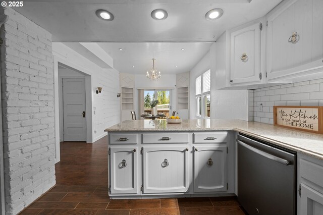 kitchen featuring a peninsula, white cabinets, tasteful backsplash, dishwasher, and a notable chandelier