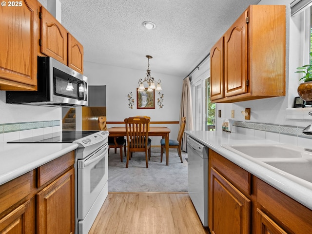 19085 SW Jaylee St, Beaverton, OR 97078 - kitchen featuring white appliances, a textured ceiling, brown cabinets, light countertops, and light wood-style floors