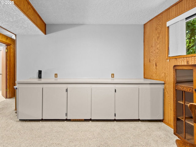 19085 SW Jaylee St, Beaverton, OR 97078 - kitchen with a textured ceiling, wood walls, light countertops, and white cabinetry