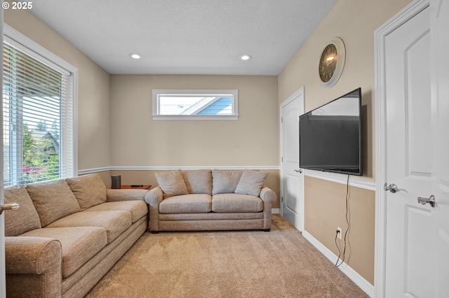 living room featuring recessed lighting, a textured ceiling, baseboards, and light carpet