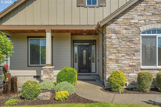 entrance to property with board and batten siding, a porch, and stone siding