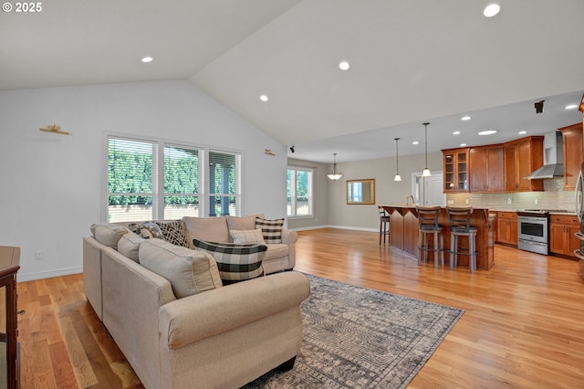 living room with recessed lighting, baseboards, high vaulted ceiling, and light wood-style floors
