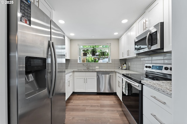 16760 SW Monaco Ln, Portland, OR 97224 - kitchen with appliances with stainless steel finishes, white cabinetry, wood finished floors, light stone counters, and recessed lighting