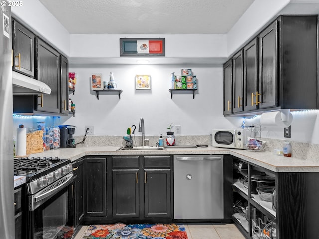 kitchen with appliances with stainless steel finishes, sink, a textured ceiling, and light tile patterned floors