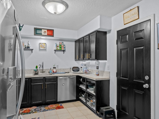 kitchen featuring stainless steel appliances, sink, a textured ceiling, and light tile patterned floors