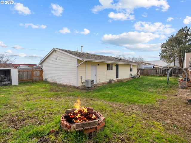 rear view of house with a yard, central air condition unit, and an outdoor fire pit