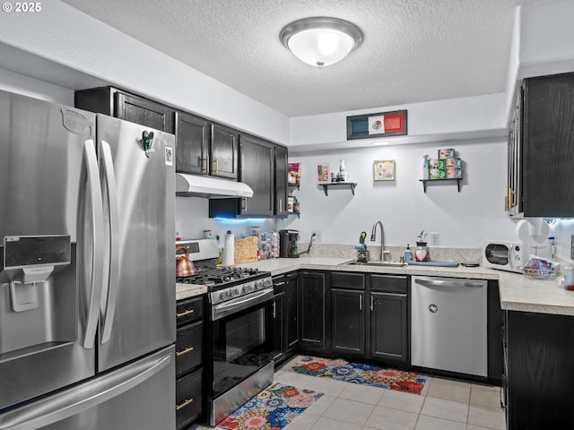 kitchen featuring stainless steel appliances, sink, light tile patterned floors, and a textured ceiling