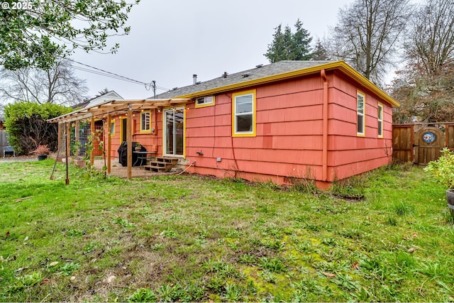 back of property with entry steps, fence, and a yard