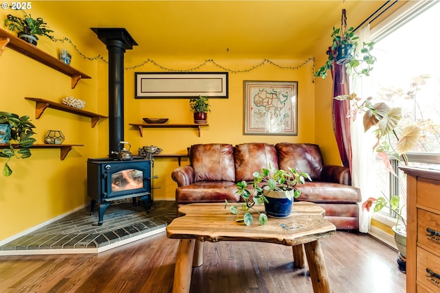 living area with baseboards, a wood stove, and wood finished floors