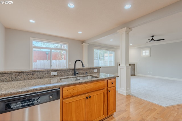 kitchen with ornate columns, sink, stainless steel dishwasher, and light stone counters