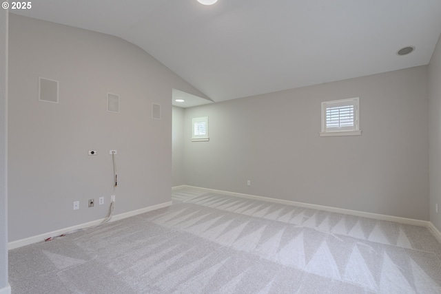 spare room with lofted ceiling, light carpet, and plenty of natural light