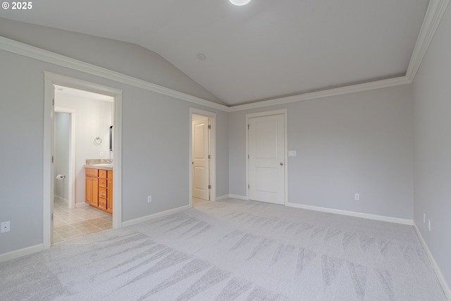 unfurnished bedroom featuring lofted ceiling, crown molding, ensuite bath, and light colored carpet