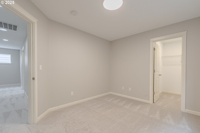 unfurnished bedroom featuring a spacious closet and light carpet