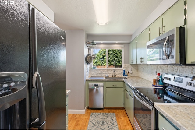 1448 S Grove Lane Ct, Sutherlin, OR 97479 - kitchen featuring stainless steel appliances, green cabinetry, a sink, and light wood-style floors