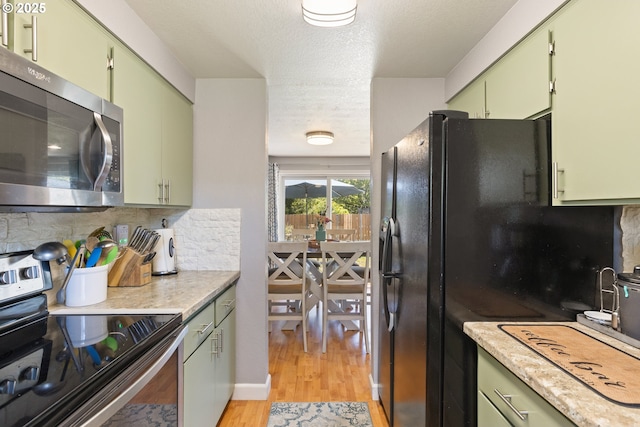 1448 S Grove Lane Ct, Sutherlin, OR 97479 - kitchen with appliances with stainless steel finishes, green cabinets, decorative backsplash, light wood-style flooring, and a textured ceiling
