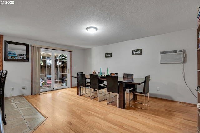 dining room with wood finished floors, a wall unit AC, and a textured ceiling