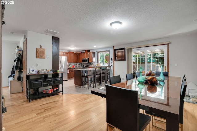 dining space featuring light wood-style flooring and a textured ceiling