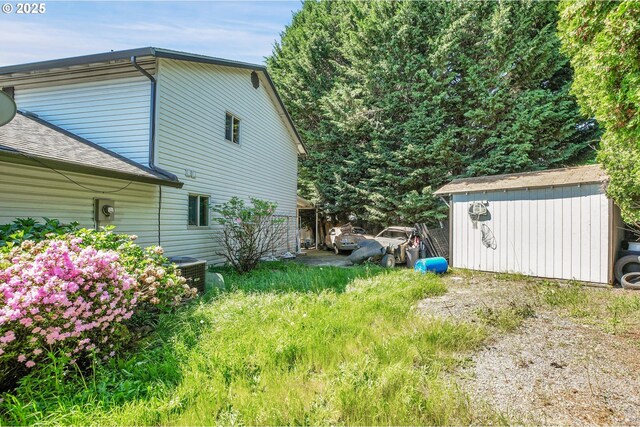 view of yard with a storage unit, an outbuilding, and central AC
