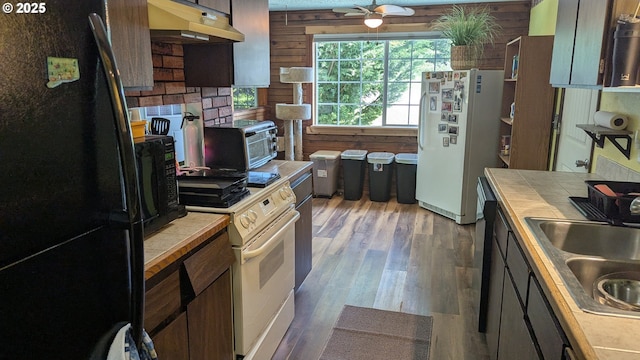 kitchen featuring ceiling fan, a sink, tile counters, under cabinet range hood, and black appliances