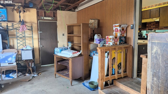 misc room with wood walls and concrete floors