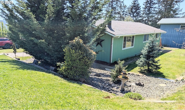 view of side of property with a yard and roof with shingles