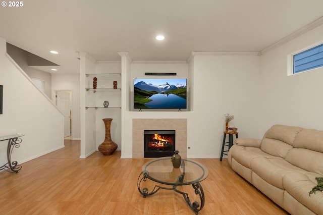 living room with baseboards, wood finished floors, ornamental molding, and a fireplace