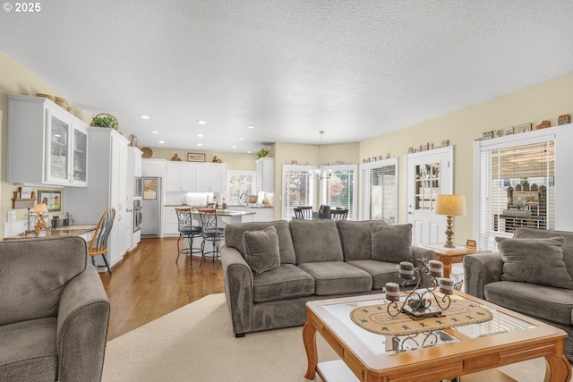 15255 NW Francesca Dr, Portland, OR 97229 - living room featuring light wood-type flooring, recessed lighting, and an inviting chandelier