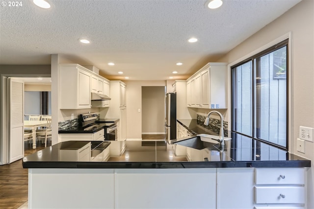 kitchen with sink, a textured ceiling, kitchen peninsula, stainless steel appliances, and white cabinets