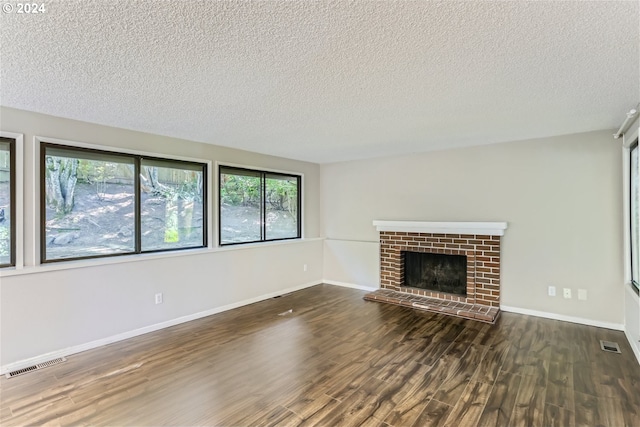 unfurnished living room with a brick fireplace, dark hardwood / wood-style floors, and a textured ceiling