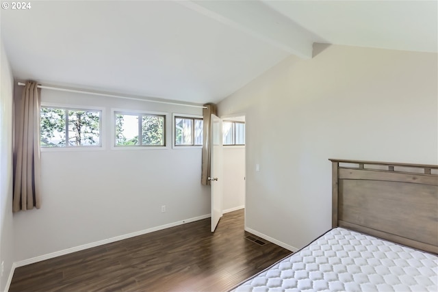 unfurnished bedroom with dark hardwood / wood-style flooring and vaulted ceiling with beams