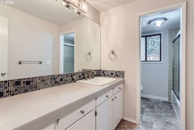 full bathroom featuring shower / bath combination with glass door, vanity, toilet, and decorative backsplash