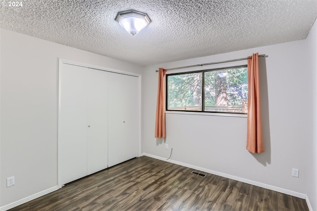 unfurnished bedroom featuring dark hardwood / wood-style floors, a closet, and a textured ceiling