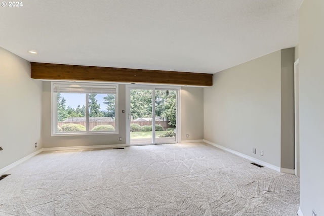 carpeted empty room featuring beamed ceiling