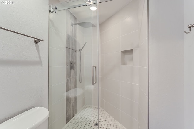 bathroom featuring a shower with door and toilet