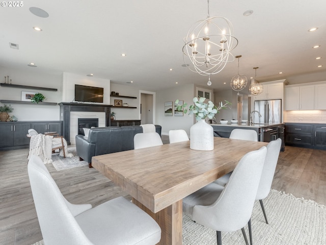 1703 S Farm View Loop, Ridgefield, WA 98642 - dining room featuring a chandelier, light wood finished floors, recessed lighting, and a glass covered fireplace