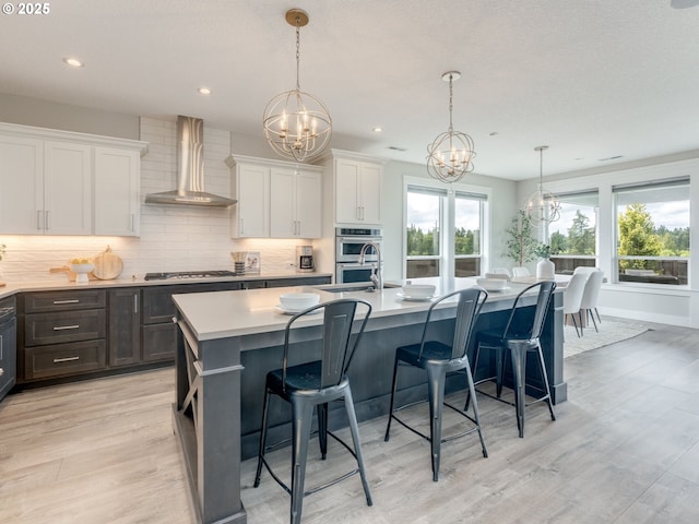 1703 S Farm View Loop, Ridgefield, WA 98642 - kitchen with wall chimney range hood, a chandelier, gas stovetop, light wood-type flooring, and recessed lighting