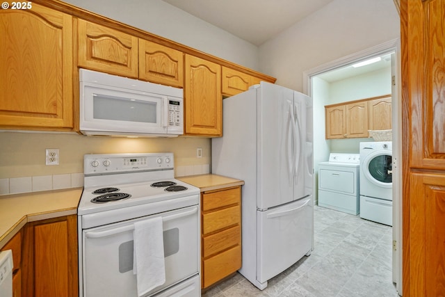 kitchen featuring white appliances and washer and clothes dryer