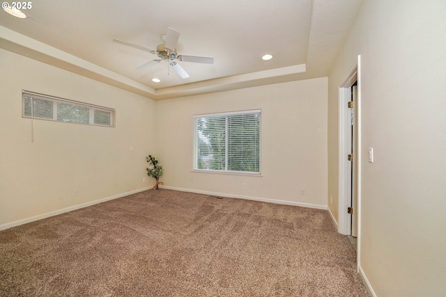 carpeted spare room featuring a tray ceiling and ceiling fan