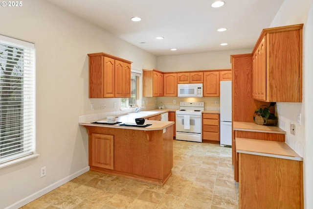 kitchen with white appliances, sink, and kitchen peninsula