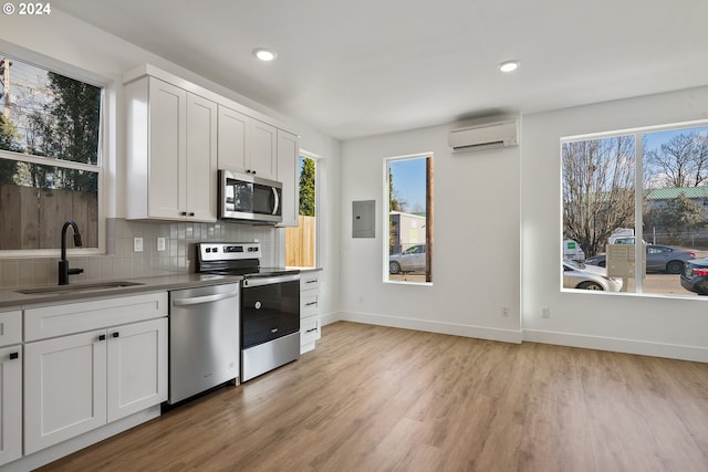 kitchen with sink, white cabinetry, a wall unit AC, stainless steel appliances, and backsplash